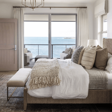 Cozy bedroom with a bed, bench, and ocean view